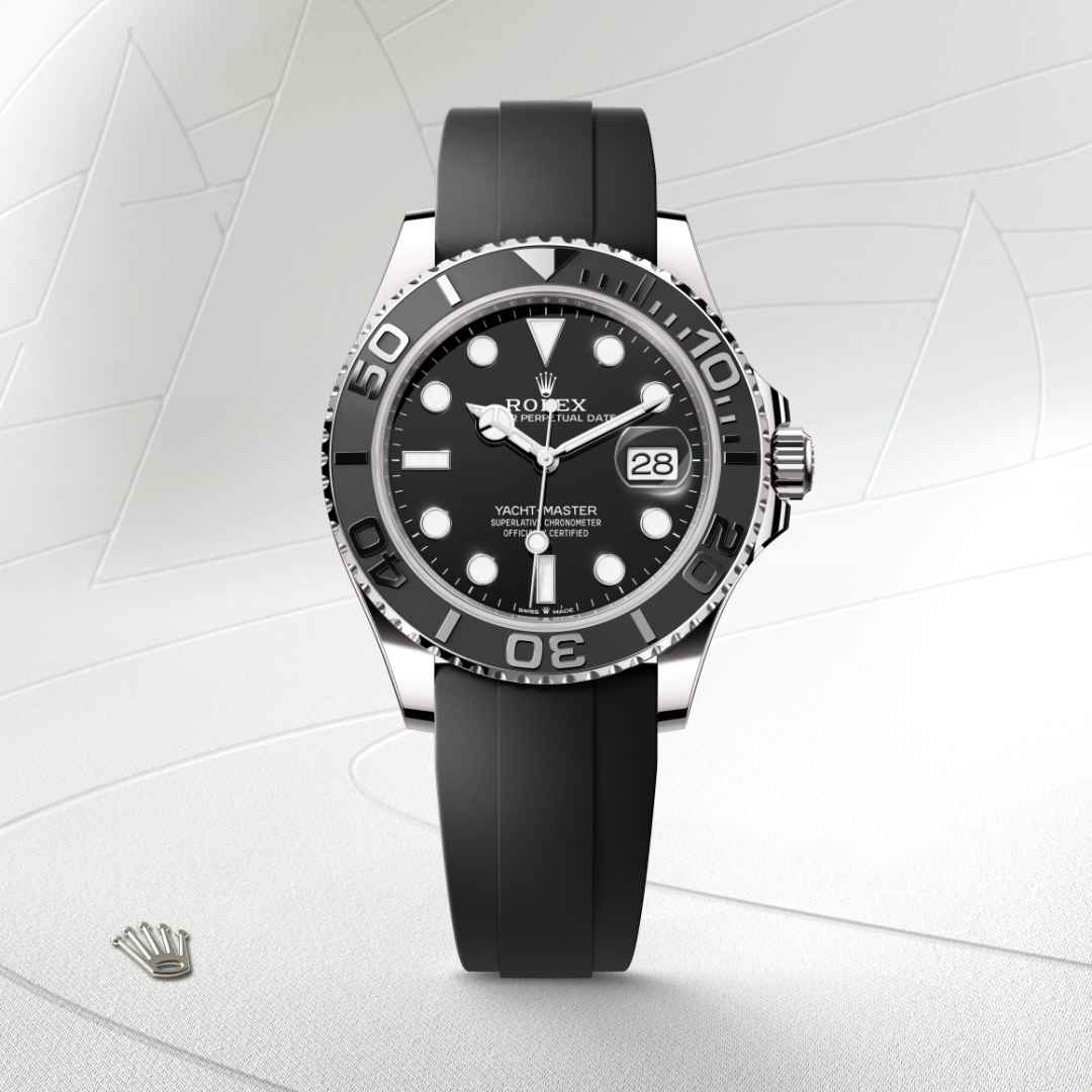 El nuevo brazalete Oysterflex del Yacht‑Master, desarrollado por Rolex y patentado, ofrece una alternativa deportiva a los brazaletes metálicos. La unión entre la caja y el cierre de seguridad Oysterlock está completamente asegurada por una lámina metálica de una aleación de titanio y níquel, lo que garantiza una gran flexibilidad. La lámina está sobremoldeada con un elastómero negro de alto rendimiento que resiste particularmente bien a las agresiones ambientales, posee una gran duración y es totalmente inocuo para el usuario. Para aumentar la comodidad, la cara interna del brazalete Oysterflex está provista de un sistema patentado de «cojines» laterales que estabilizan el reloj en la muñeca. Este brazalete está equipado con un cierre de seguridad Oysterlock en Oro blanco de 18 quilates. Dispone asimismo del sistema de extensión Rolex Glidelock, desarrollado por la marca y patentado. Este ingenioso mecanismo de cremallera, integrado en el cierre, permite un ajuste preciso —sin necesidad de herramientas— de la longitud del brazalete de unos 15 mm en incrementos de aproximadamente 2,5 mm.